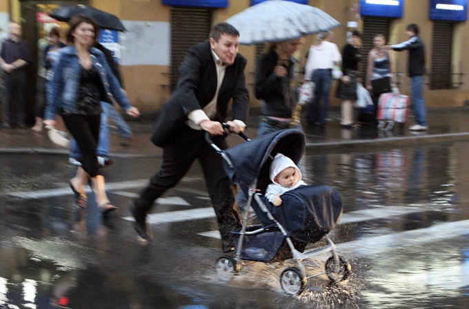 Мужчина с ребенком в коляске переходит дорогу по пешеходному переходу. Александр Петросян/Коммерсантъ