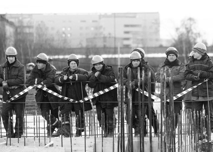 Рабочие за оградой,  «Законопроект о ФКС, тот же 94-ФЗ, только вид сбоку» Фото: Илья Питалев/Коммерсантъ